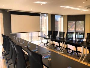 a conference room with a large projection screen and tables and chairs at Mythos Boutique Hotel in Kigali