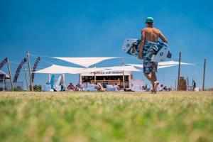 un hombre caminando con una tabla de surf en un campo en ProKite Alby Rondina - RESORT - en Birgi Vecchi