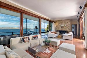 a living room with white furniture and large windows at Es Balco, Villa over the mediterranean sea with private beach access in Cielo de Bonaire 