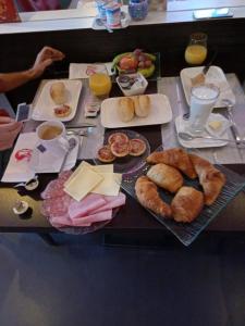 a table with a breakfast of croissants and other breakfast foods at Hotel L'Empire in Olm