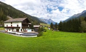 a building in a green field with mountains in the background at Hotel Garni Bergwelt in Sankt Anton am Arlberg