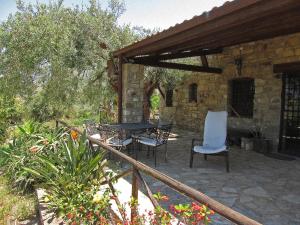 een patio met een tafel en 2 stoelen en een stenen gebouw bij Villa Degli Ulivi in Collesano