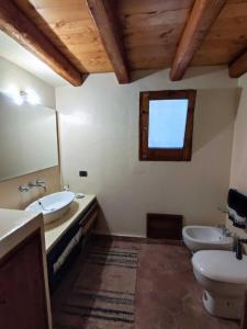 een badkamer met 2 wastafels, een toilet en een raam bij Villa Degli Ulivi in Collesano