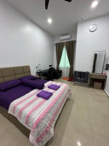 a bedroom with a bed with purple pillows on it at Homestay SJTM in Cukai