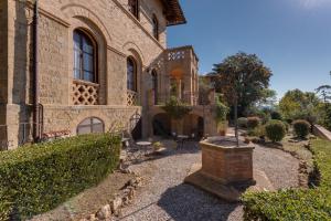 une ancienne maison en briques avec un jardin en face de celle-ci dans l'établissement Appartamenti Villa Mascagni, à Volterra
