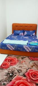 a bed with a blue comforter and red roses at RAYYAN HOMESTAY SERI ISKANDAR PERAK in Kampong Bota Road