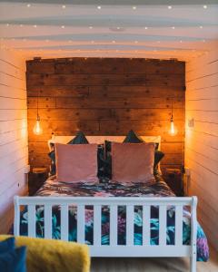 a bedroom with a white bed with a wooden headboard at The Horrrsebox Tinyhouse Glamping in Garadice