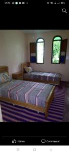 2 Betten in einem Schlafzimmer mit 2 Fenstern in der Unterkunft Maison Ait Mizane in Imlil