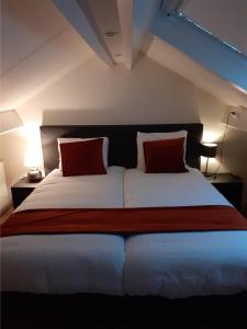 a bedroom with a large bed with two red pillows at Bed & Breakfast Trouwborst in Rhenen