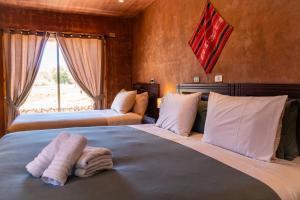 a bedroom with two beds with towels on them at Foresta Atacama Lodge in San Pedro de Atacama