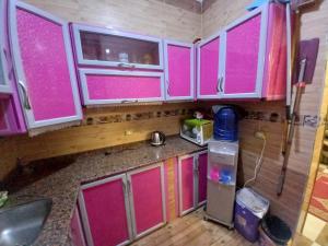 a kitchen with pink doors and a counter top at Sabrina home in Aswan