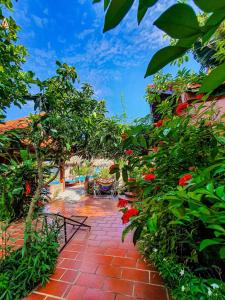 ニンビンにあるTrang An Village Homestayの赤い花とレンガ造りの散歩道がある庭園