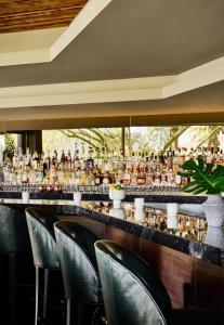 un bar con sillas negras y un mostrador con muchas botellas en Sanctuary Camelback Mountain, A Gurney's Resort and Spa en Scottsdale