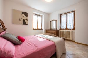sypialnia z łóżkiem z różową pościelą i oknami w obiekcie [Presolana Home] relax con vista - SELF CHECK IN w mieście Castione della Presolana