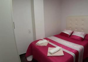 um quarto com uma cama vermelha e branca com toalhas em Angel em Zamora