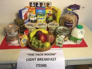 una tavola con un cesto di frutta e altri prodotti alimentari di The Tack Room - a comfy cabin in North Devon a Bideford