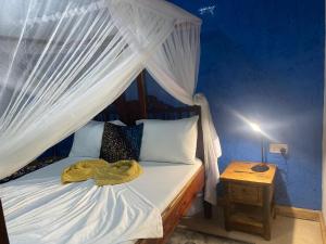 a bedroom with a bed with a canopy at Mbuyuni Beach Village in Jambiani