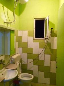 a green and white bathroom with a toilet and a window at Guesthouse Aleksander in Berat