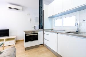 eine Küche mit weißen Schränken und einem Waschbecken in der Unterkunft Charming 2 Bedroom Apartment Triana Bridge By Oui Seville in Sevilla