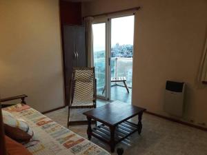 a room with a bed and a table and a balcony at IEMANJA Depto Villa Gesell in Villa Gesell