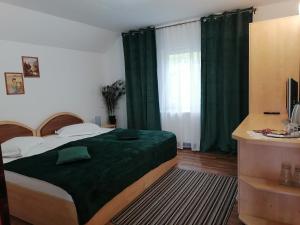 a bedroom with a bed with green sheets and a window at Motorom in Zărneşti