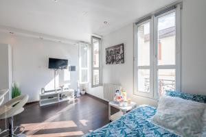 a living room with a bed and a tv and windows at Ma Douceur Paris La Défense in Courbevoie