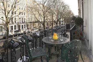 uma varanda com mesas e cadeiras numa rua da cidade em Beaufort House - Knightsbridge em Londres