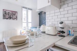 a white kitchen with a counter with glasses on it at Ma Douceur Paris La Défense in Courbevoie