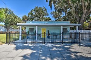 a white house with a yellow door behind a fence at Serene Daytona Beach House with Private Yard! in Daytona Beach