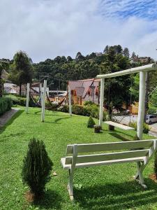un parco con panchina e amaca in erba di Casa de Campos Capivari House a Campos do Jordão