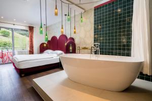 a bathroom with a tub and a bedroom with a bed at Hotel Heiligenstein in Baden-Baden