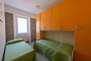 um pequeno quarto com 2 camas e armários laranja em PODERE PRATIZZOLI em Tolè