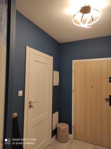 - une salle de bains avec des murs bleus, une porte et une lumière dans l'établissement Apartament na Wzgórzu Niebieski, à Łańcut