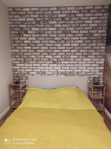 - une chambre avec un lit jaune et un mur en briques dans l'établissement Apartament na Wzgórzu Niebieski, à Łańcut
