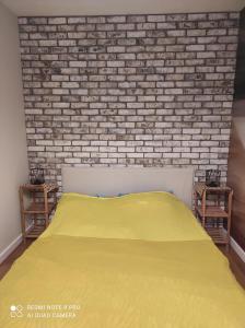 a bedroom with a yellow bed and a brick wall at Apartament na Wzgórzu Niebieski in Łańcut