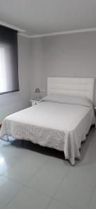 a white bedroom with a large bed in a room at Apartamento Alba in Portonovo