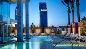 a hotel swimming pool with chairs and palm trees at StripViewSuites Two-Bedroom Con-Joined Exclusive Condo in Las Vegas