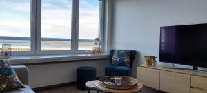 a living room with a flat screen tv and a chair at Vakantie-appartement La Régence @ Oostende in Ostend