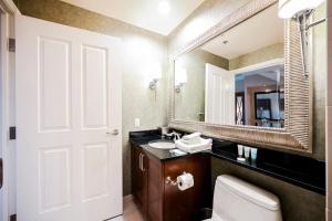 a bathroom with a toilet and a sink and a mirror at StripViewSuites Penthouse Two-Bedroom Conjoined Suite in Las Vegas