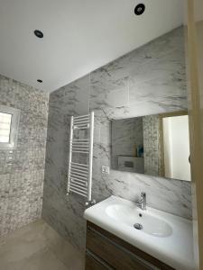 ein Bad mit einem Waschbecken und einem Spiegel in der Unterkunft La maison du Jasmin in Mahdia