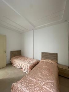 La maison du Jasmin في المهدية: سريرين في غرفة بجدران بيضاء
