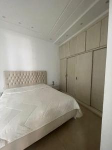 La maison du Jasmin في المهدية: غرفة نوم بيضاء مع سرير كبير وخزانة