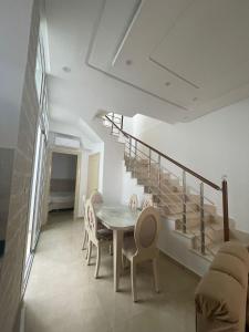ein Esszimmer mit einem Tisch, Stühlen und einer Treppe in der Unterkunft La maison du Jasmin in Mahdia