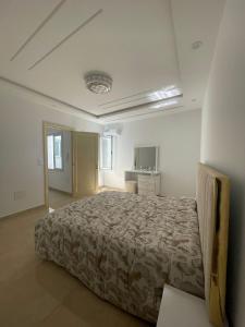 una camera da letto con un grande letto in una stanza bianca di La maison du Jasmin a Mahdia