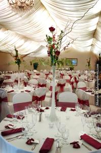 a large room with white tables and chairs with red napkins at Lake Natoma Inn in Folsom