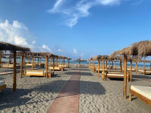 una playa con bancos y sombrillas de paja y el océano en Villa Hanna, en Ulcinj