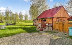 a log cabin with a red roof next to a pond at Pet Friendly Home In Gubin With Sauna in Gubin