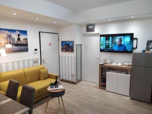 San Siro Dream Home -Apartment with garage-Milano في ميلانو: غرفة معيشة مع أريكة صفراء وتلفزيون بشاشة مسطحة
