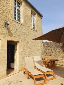a patio with two chairs and a table in front of a building at Chambres Résidentielles avec cuisine au Manoir de Mathan à Crépon 5 mn D'Arromanches et 10 mn de Bayeux in Crépon