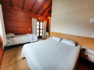 a bedroom with a white bed and a window at Hospedagem Morada dos Sonhos in Urubici